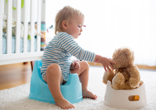 Kleinkind auf Töpfchen mit Teddybär, Töpfchentraining Tipps für Eltern.