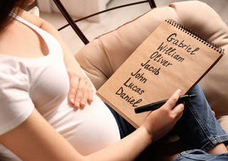 Schwangere Frau mit Notizbuch voller Babynamen, Blog über Namenswahl.