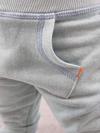 Hellgrüne Bio-Baumwoll-Krabbelhose Froggy von Living Crafts, Nahaufnahme der Tasche mit orangen Nähten.