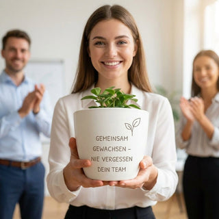 Praktikantin erhält gravierten Blumentopf als Abschiedsgeschenk vom Team